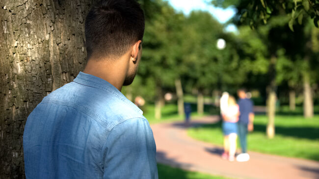 Man secretly spying loving couple walking on date outdoors, jealous ex-boyfriend