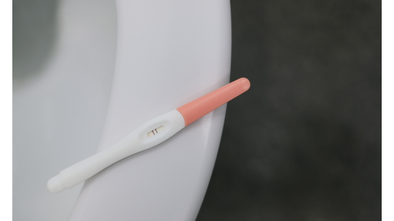 Positive Pregnancy Test Stick Lies On A Toilet Bowl.
