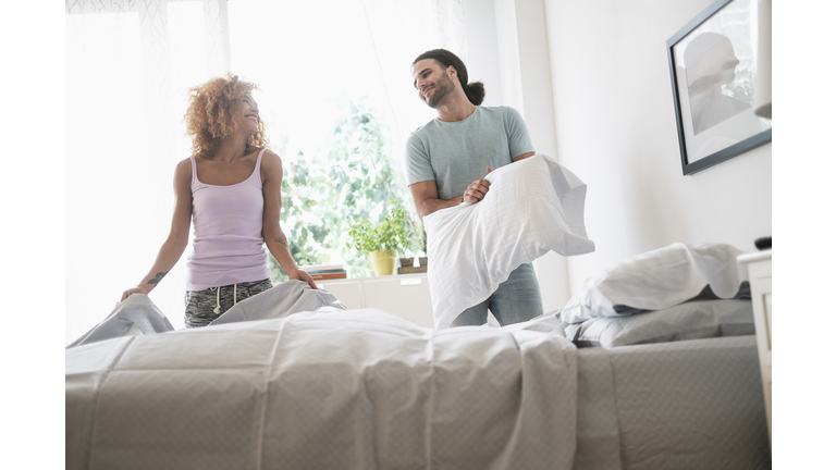 Young couple making bed in morning