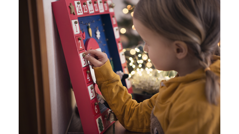 Girl (4-5) opening Christmas advent calendar