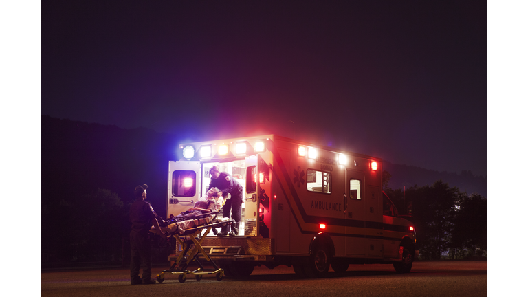 Paramedics carrying patient in ambulance at night