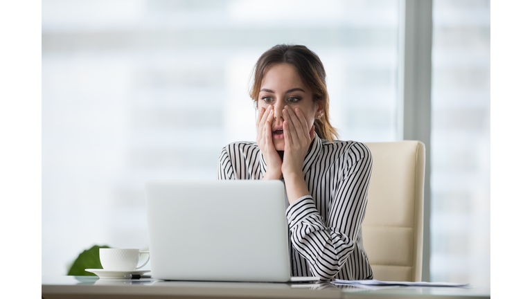 Shocked young woman looking at laptop screen.