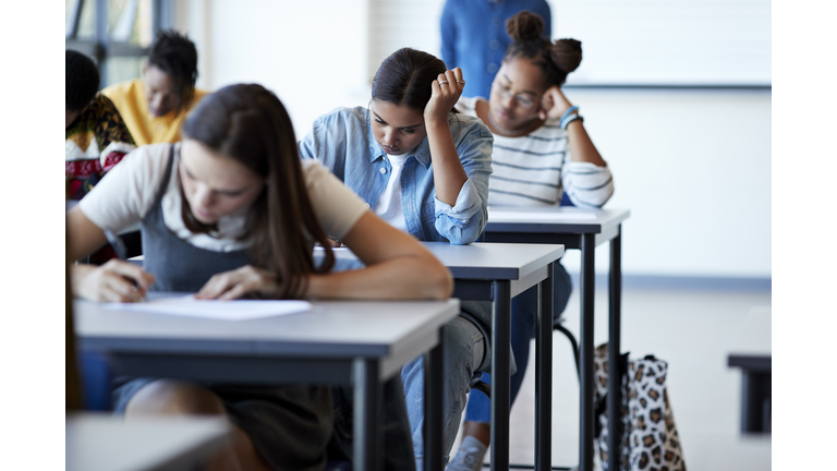 Young multi-ethnic female students writing exams