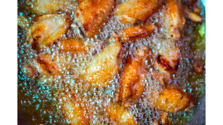 Close up fried chicken wings in boiling oil, in a cast iron frying.