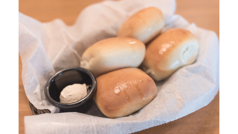 Texas Roadhouse Rolls with Cinnamon Honey Butter in a basket.;