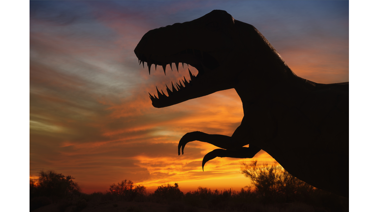 Silhouette of dinosaur sculpture at sunset, Moab, Utah, USA