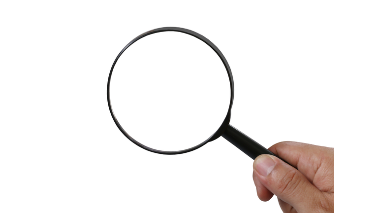 Close-Up Of Hand Holding Magnifying Glass Against White Background