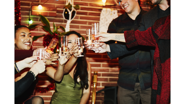 Smiling friends toasting with champagne glasses during holiday party in home