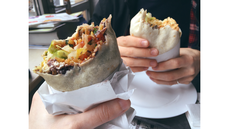 Cropped Hands Holding Burritos At Restaurant