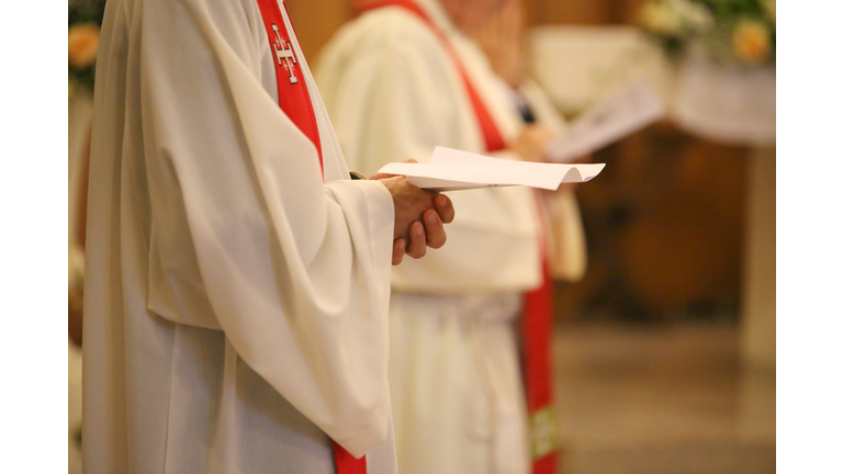 priest with hands joined in prayer during Holy Mass in church