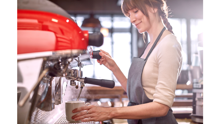 Barista using espresso machine in coffee shop