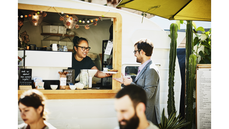 Businessman receiving food order from owner of food truck