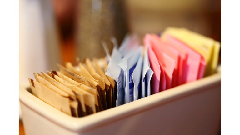 Close-Up Of Sugar And Sweetener Packets In Container At Cafe