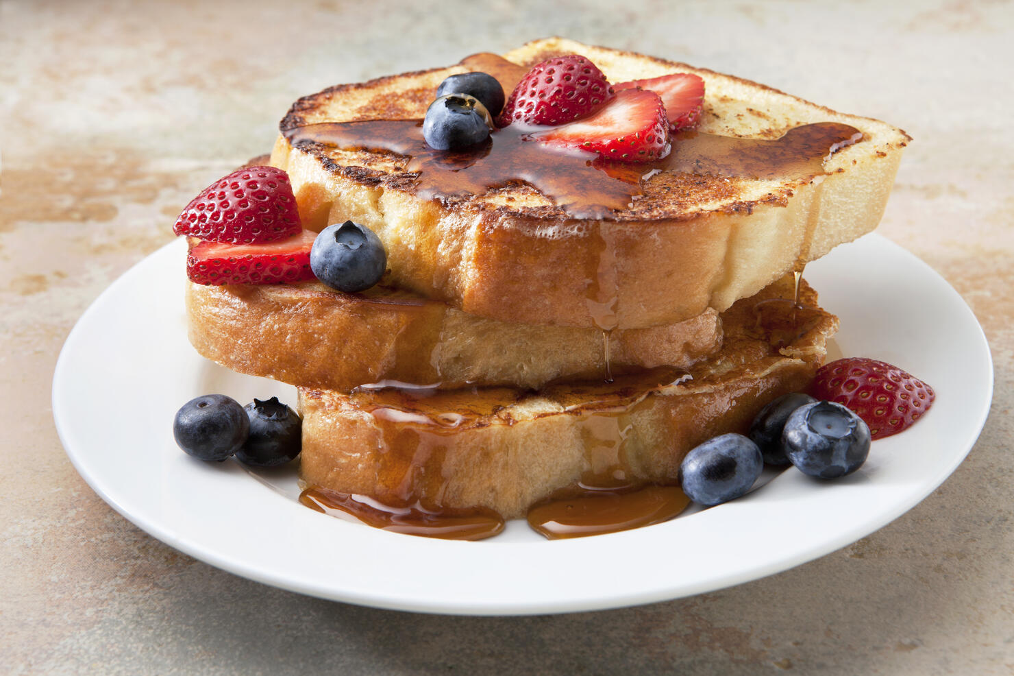 French Toast With Fruit and Syrup on a Marble Countertop.