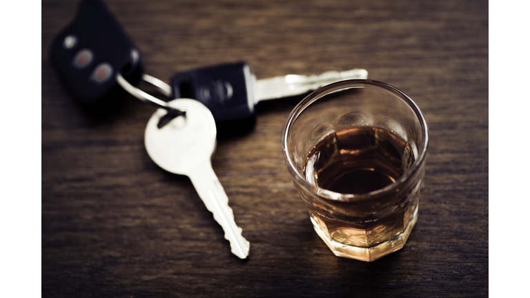 A glass of whisky and a set of car keys on a wooden table