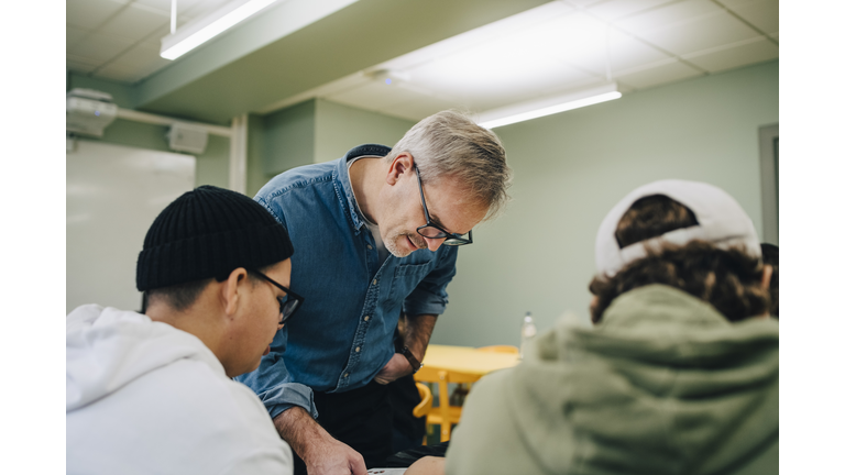 Male teacher teaching students in classroom