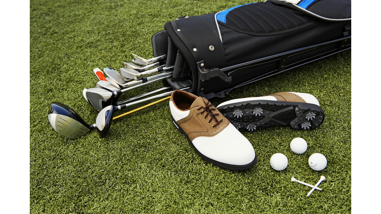 Golf clubs, golf bag, shoes, balls and tees on artificial turf