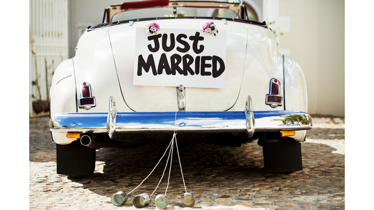 Just Married Sign And Cans Attached To Car's Trunk