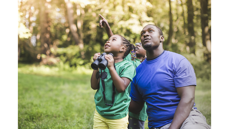 Young father with son and daughter bird watching in eco forest camp