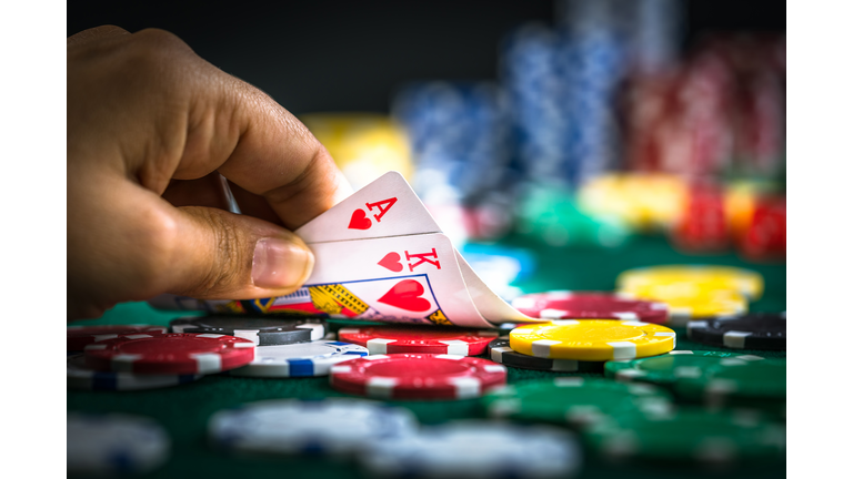 Gambling Hand Holding Poker Cards and Money Coins Chips