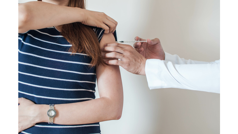 A doctor is giving a vaccine to a young woman