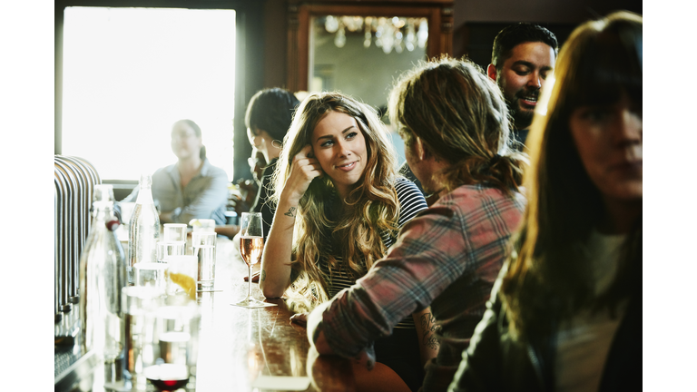 Smiling woman flirting with man while sitting in bar