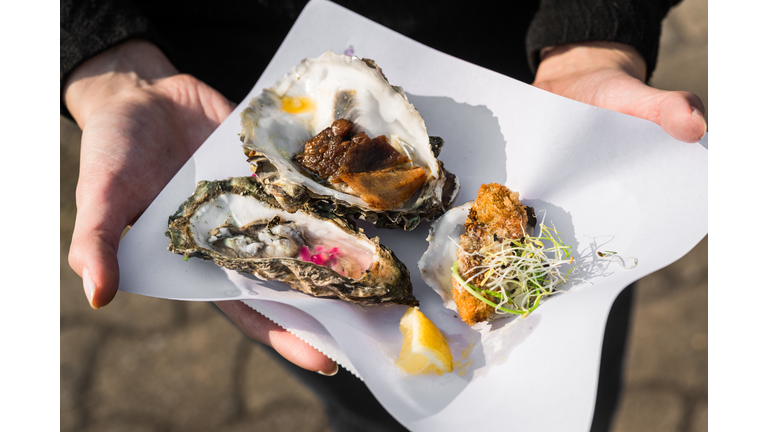 Close up of raw, fried, and smoked gourmet oysters at a street food market fair festival