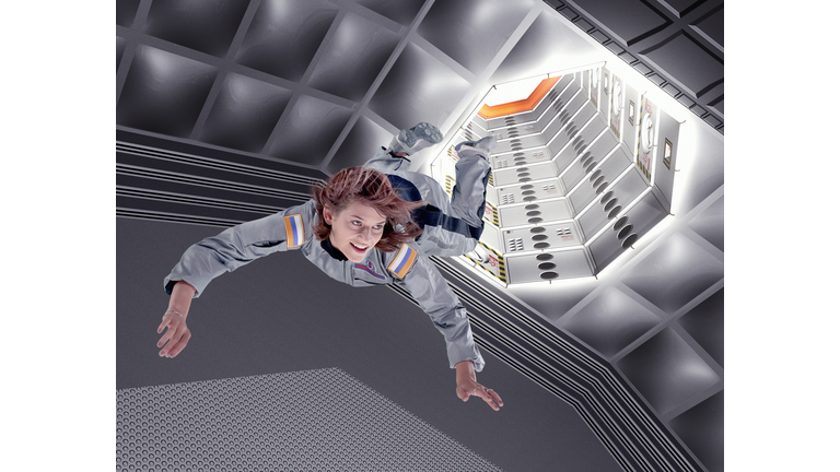 Female astronaut floating in space station (Digital Composite)