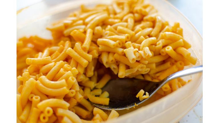 leftover bright orange kraft dinner macaroni and cheese being spooned for reheating