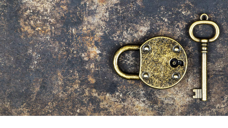 Escape room concept, vintage gold key and locked padlock