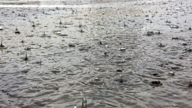 Close-up of a large puddle  of water with splashing raindrops during a downpour