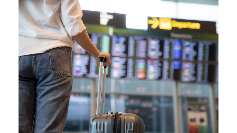 Female traveller standing in front of Flight display schedule in the International airport