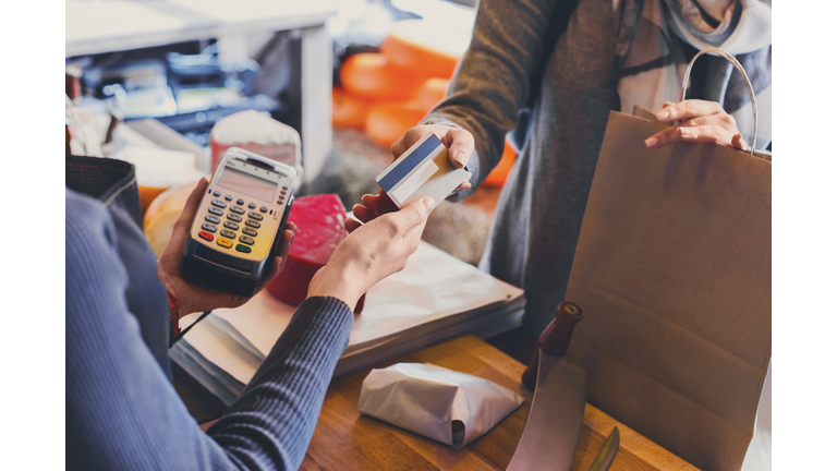 Customer paying for order of cheese in grocery shop.