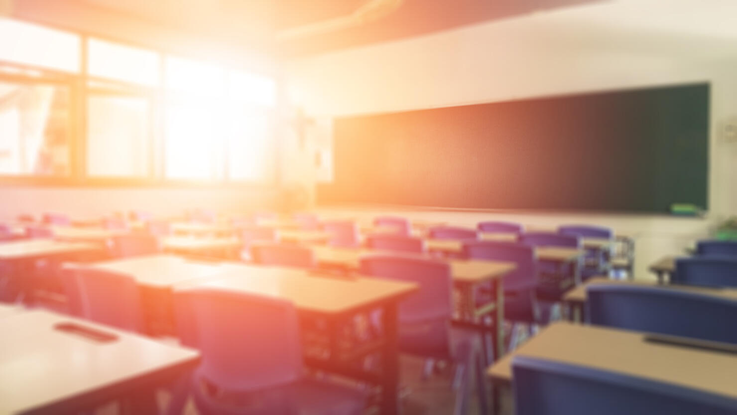 School classroom in blur background without young student; Blurry view of elementary class room no kid or teacher with chairs and tables in campus.