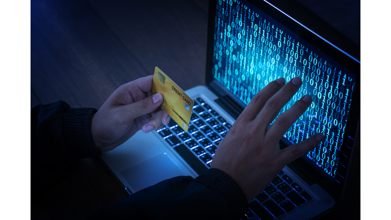 Hands of anonymous hackers holding credit card