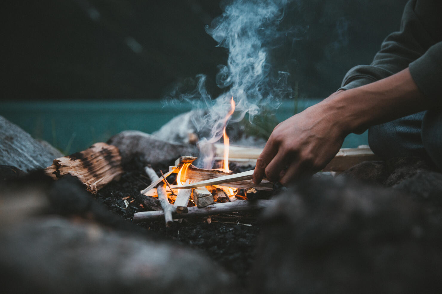 Midsection Of Man Sitting By Campfire