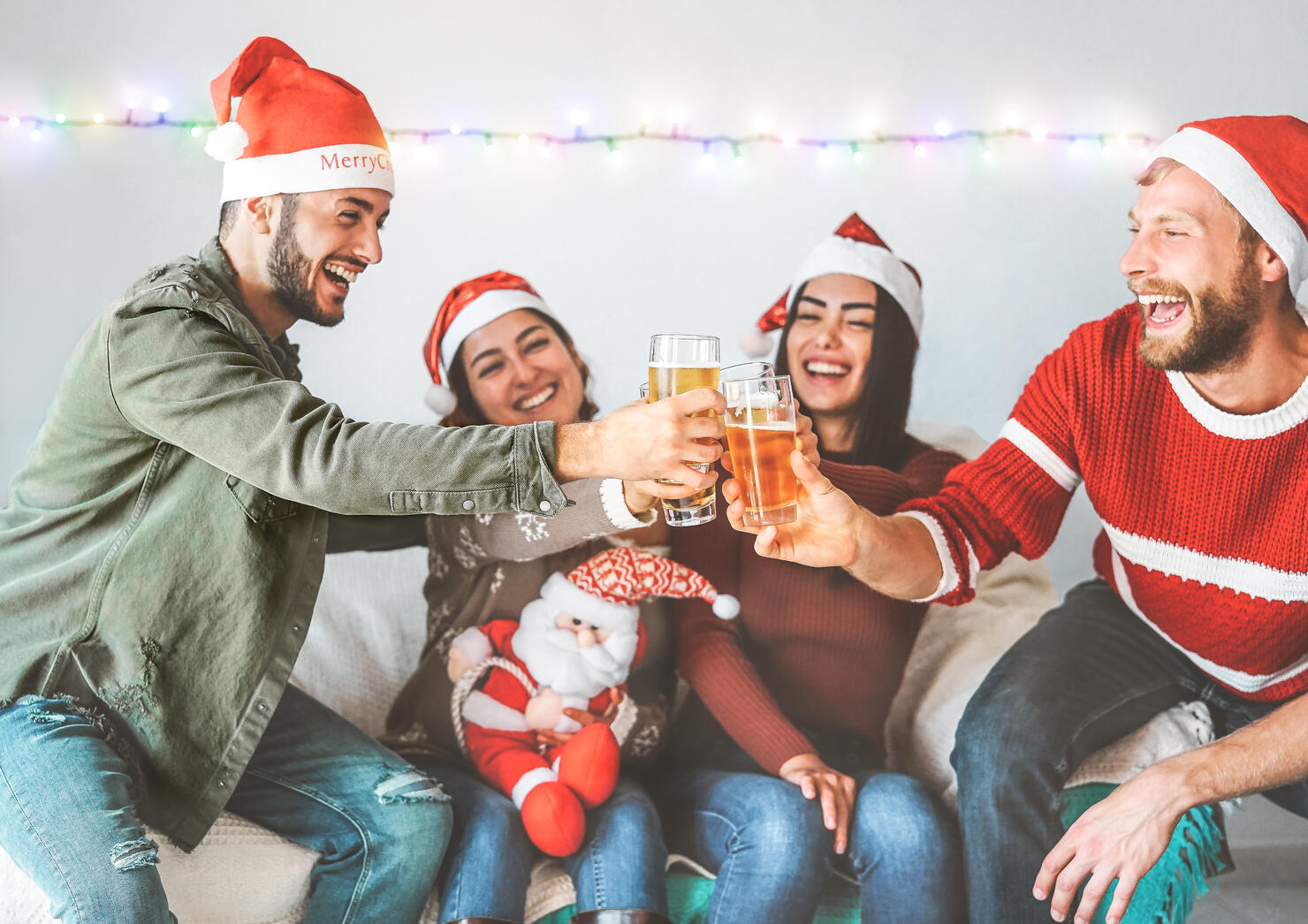Group of happy friends cheering with beer at christmas party - Young people having fun drinking and enjoying together xmas holidays - Friendship, drinks and youth celebrating lifestyle concept