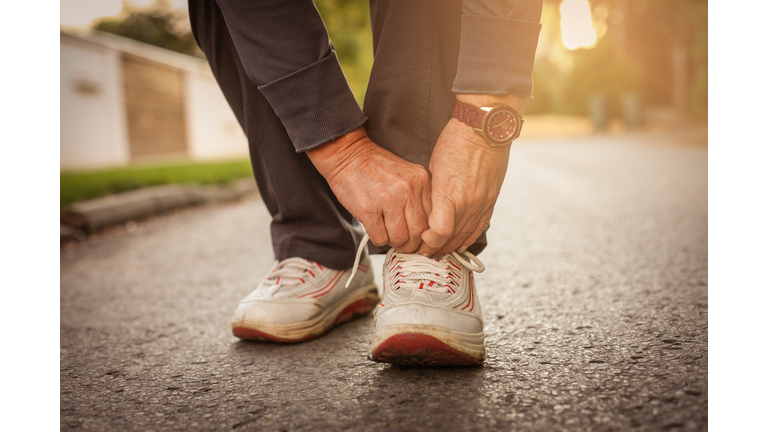 Senior woman hands tying sneakers. Close up.