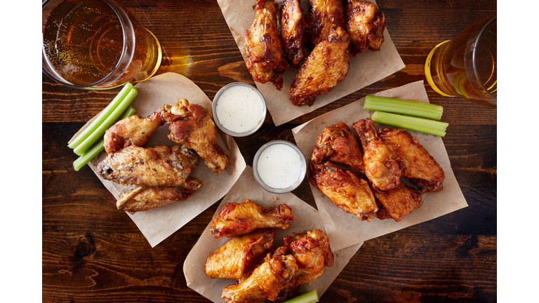 overhead view of four different flavored chicken wings with beer