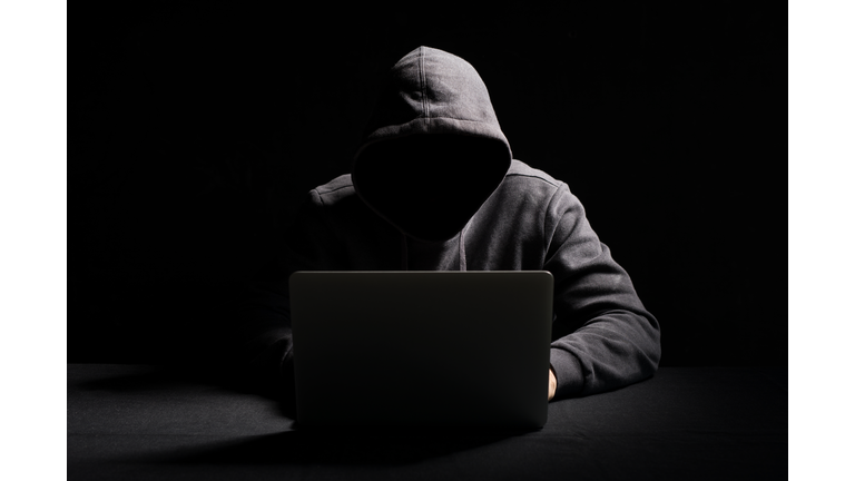 Hacker working on laptop in the dark