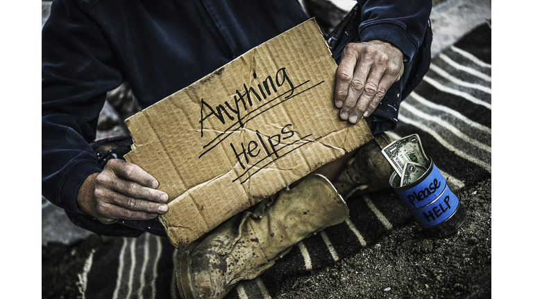 Homeless man with money tin begging for money