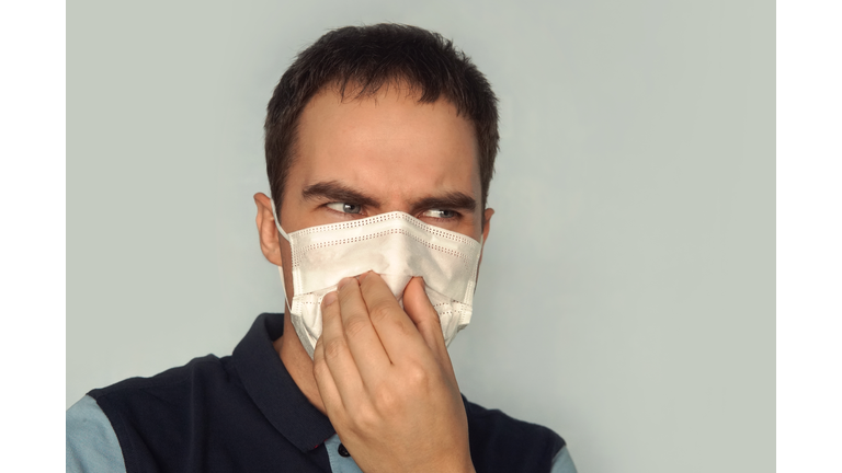 young father holding dirty dirty diaper in one hand fingers with gas mask over white background. Unpleasant smell stink. bad ecology gas pollution