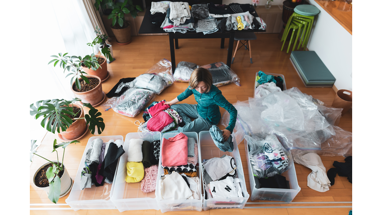 Woman organizes clothes in living room of her home
