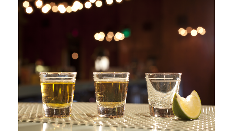 Shots of various types of tequila on bar with lime wedge