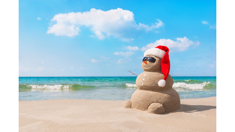 Christmas snowman in santa hat at sandy beach