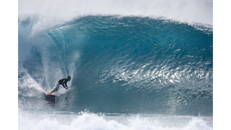 A young man surfing a big wave at Pipeline, on the north shore of Oahu, Hawaii.