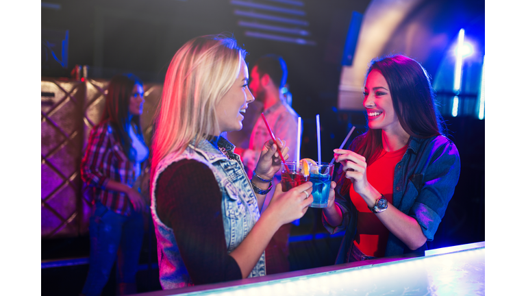 Two cheerful female friends having fun in night club