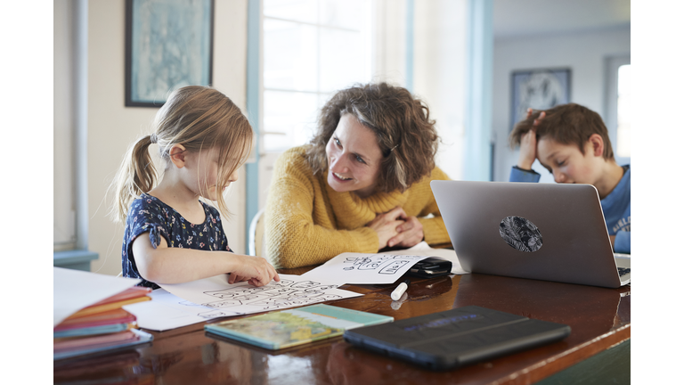 Mother homeschooling daughter and son at table