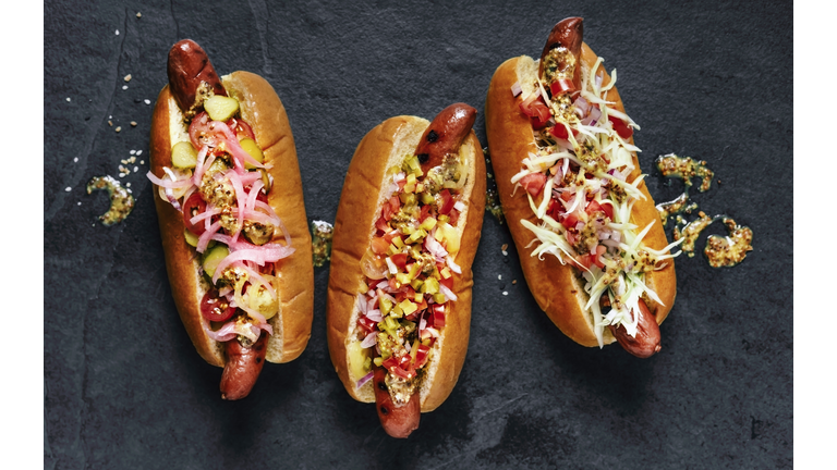 Three gourmet hot dogs on black background