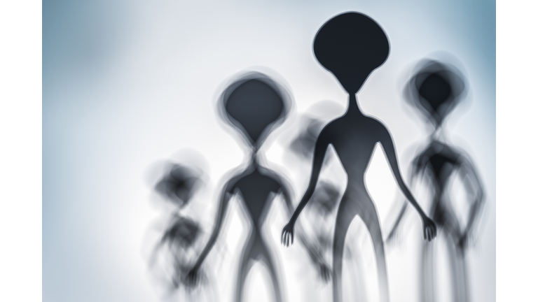 Silhouettes of spooky aliens and bright light on behind them